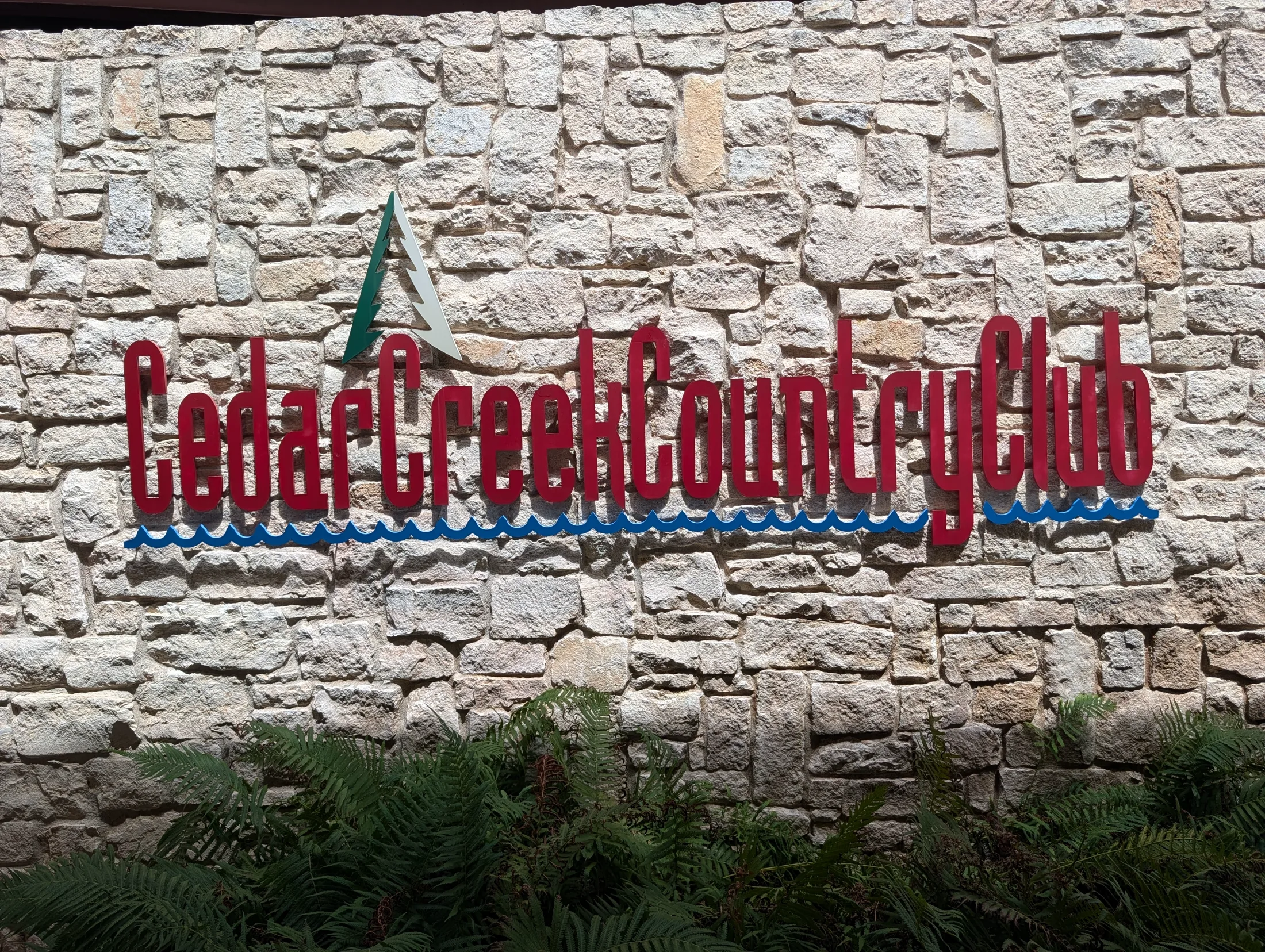 Cedar Creek Country Club sign set into a stone wall